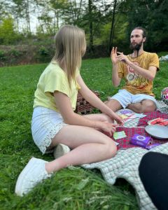Two people sitting on blankets in a park, playing The Well-being Game with cards laid out between them.