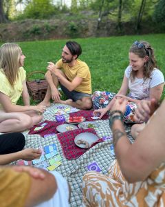 Group of people sitting on picnic blankets in a park, talking while The Well-being Game cards are laid out between them.